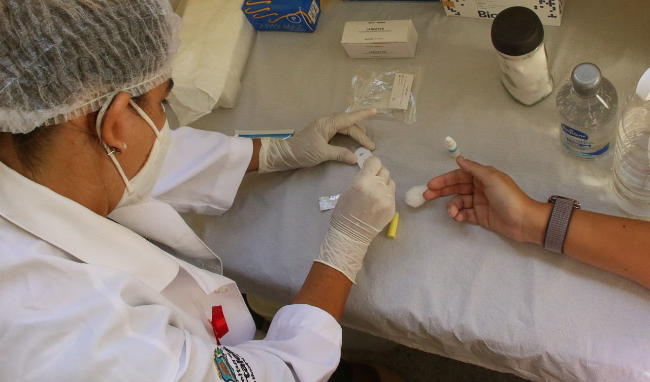 enfermeira fazendo o teste HIV em uma paciente. Só as mãos delas são mostradas